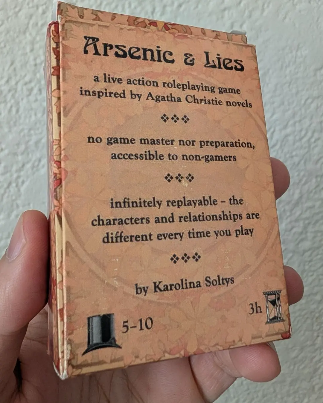 The back of the Arsenic and Lies box: a live-action roleplaying game inspired by Agatha Christie, no game master or preparation, 5 to 10 players, three hours, by Karolina Soltys.