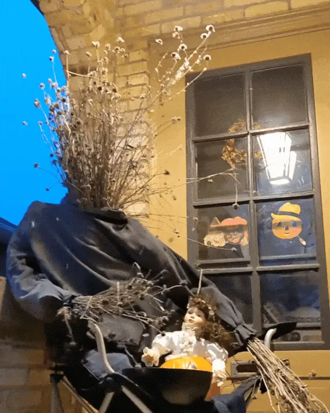 A scarecrow set up by the front door for a Halloween party