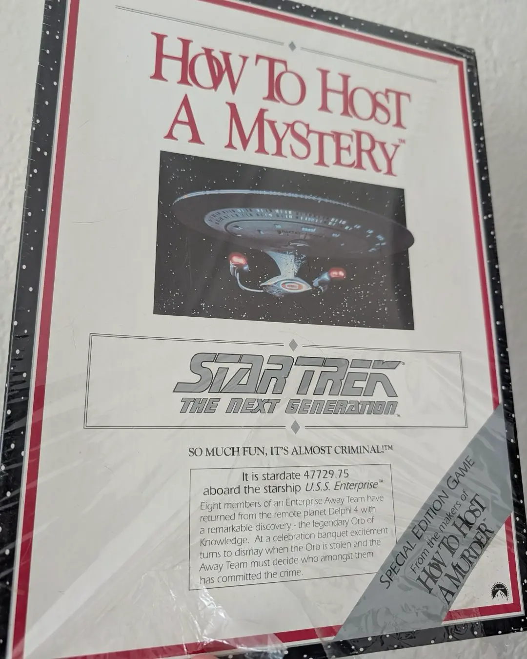 A shrink-wrapped How to Host a Mystery: Star Trek The Next Generation special edition box, showing the Enterprise over a starfield.