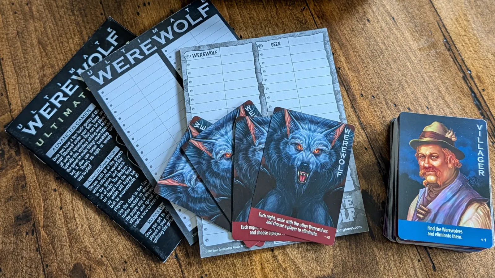 Contents of the social deduction game Ultimate Werewolf, including werewolf and villager cards.